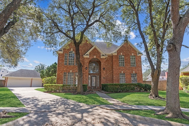 traditional-style home featuring a front yard, brick siding, fence, and a detached garage