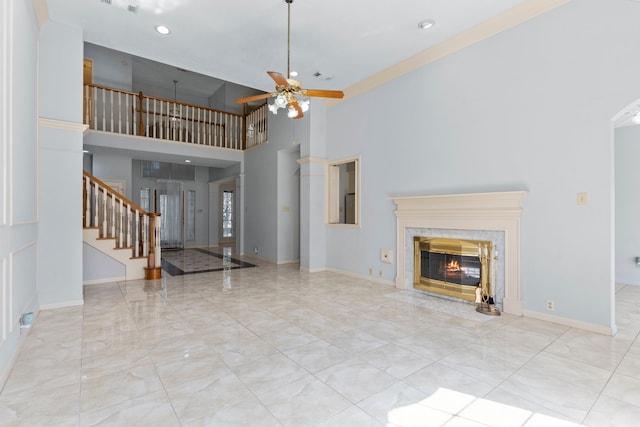 unfurnished living room with a premium fireplace, stairway, a ceiling fan, and baseboards