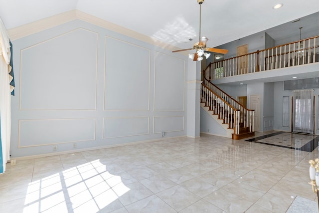 interior space featuring ceiling fan, a high ceiling, stairway, and a decorative wall