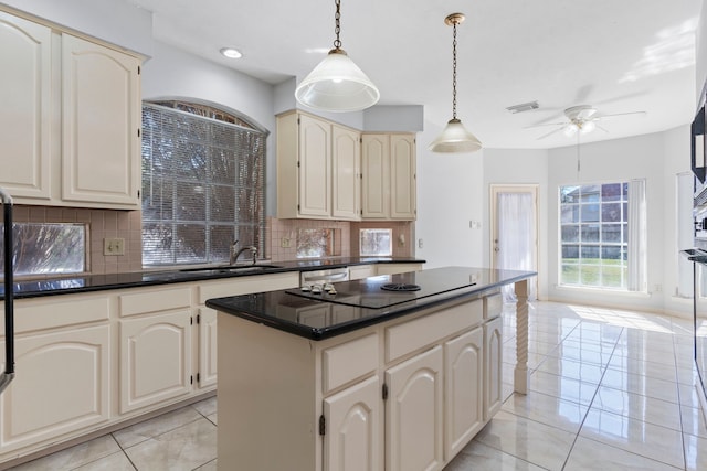 kitchen with dark countertops, cream cabinets, pendant lighting, and a center island