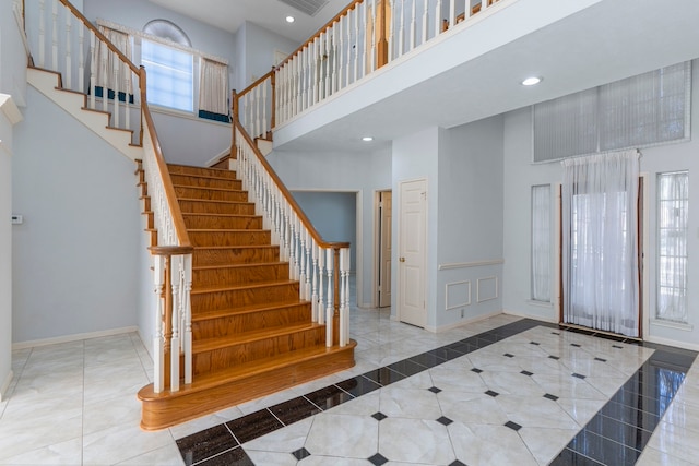 stairway with recessed lighting, visible vents, a high ceiling, baseboards, and tile patterned floors