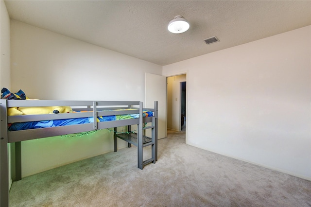 bedroom featuring a textured ceiling and light carpet