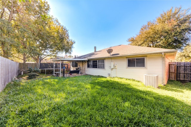 rear view of house with a lawn, cooling unit, a patio, and a trampoline