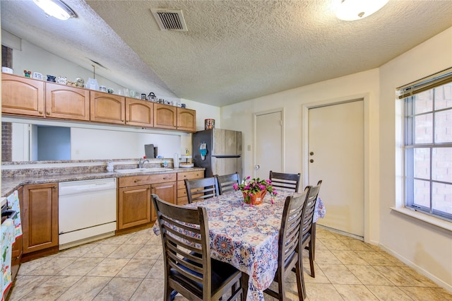 interior space featuring a textured ceiling, white dishwasher, stainless steel refrigerator, and lofted ceiling