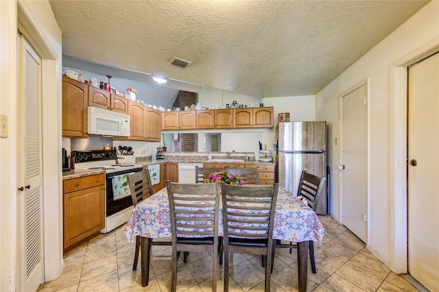 kitchen with light tile patterned flooring, white appliances, sink, and vaulted ceiling