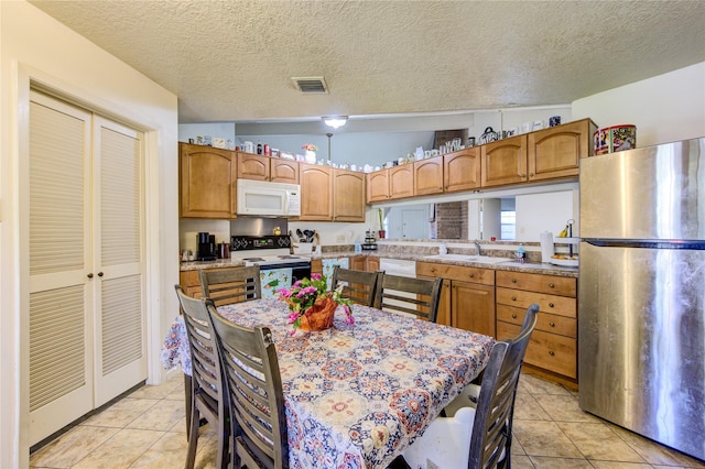 kitchen with vaulted ceiling, sink, light tile patterned floors, and white appliances