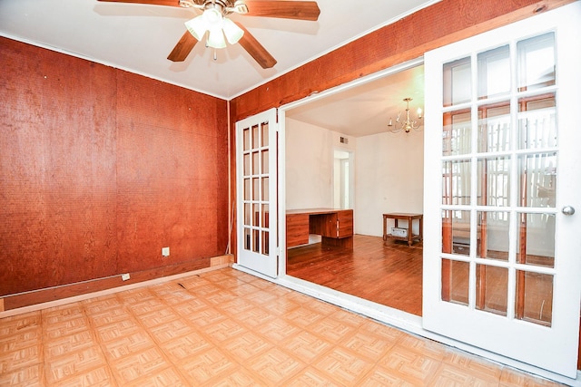 unfurnished room featuring ceiling fan with notable chandelier, light parquet flooring, and french doors