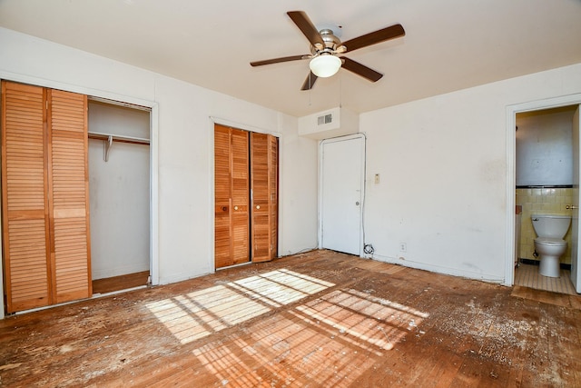 unfurnished bedroom featuring hardwood / wood-style floors, connected bathroom, ceiling fan, and multiple closets