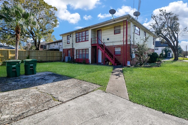 rear view of house featuring central AC unit and a lawn