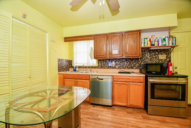 kitchen with light wood-type flooring, stainless steel appliances, backsplash, and sink