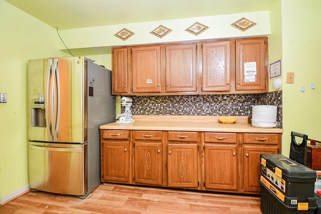 kitchen featuring stainless steel fridge, light hardwood / wood-style floors, and tasteful backsplash