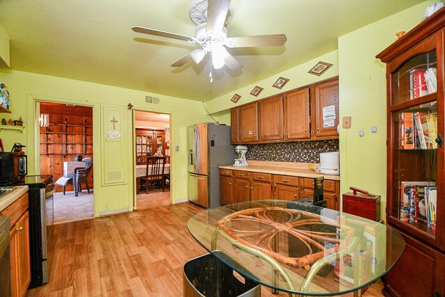 kitchen featuring ceiling fan, stainless steel fridge with ice dispenser, light hardwood / wood-style flooring, backsplash, and range with electric stovetop