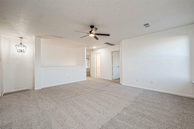 unfurnished room featuring ceiling fan with notable chandelier, carpet, and a textured ceiling