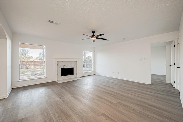 unfurnished living room with a fireplace, ceiling fan, plenty of natural light, and hardwood / wood-style floors