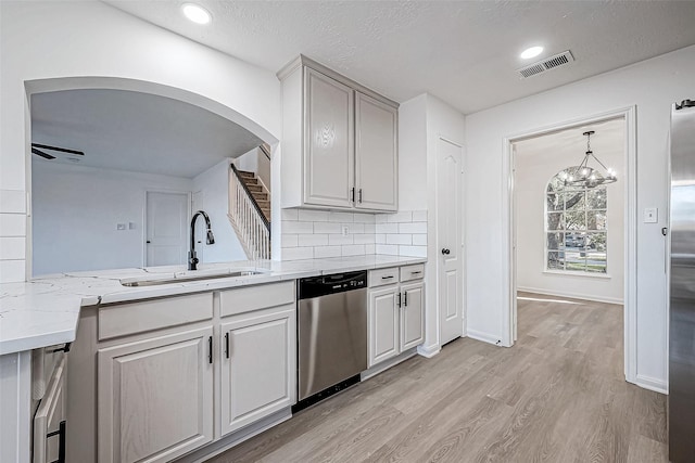 kitchen with sink, decorative backsplash, appliances with stainless steel finishes, ceiling fan with notable chandelier, and light wood-type flooring