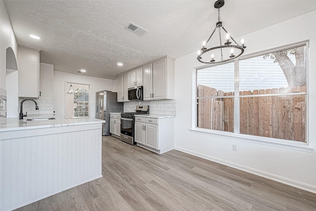 kitchen with backsplash, white cabinets, sink, light wood-type flooring, and stainless steel appliances