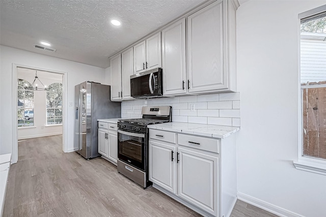 kitchen featuring plenty of natural light, light wood-type flooring, a textured ceiling, and appliances with stainless steel finishes