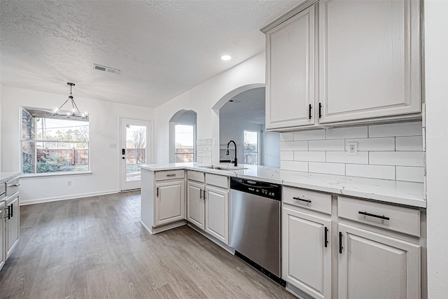 kitchen with dishwasher, sink, light hardwood / wood-style flooring, a notable chandelier, and kitchen peninsula