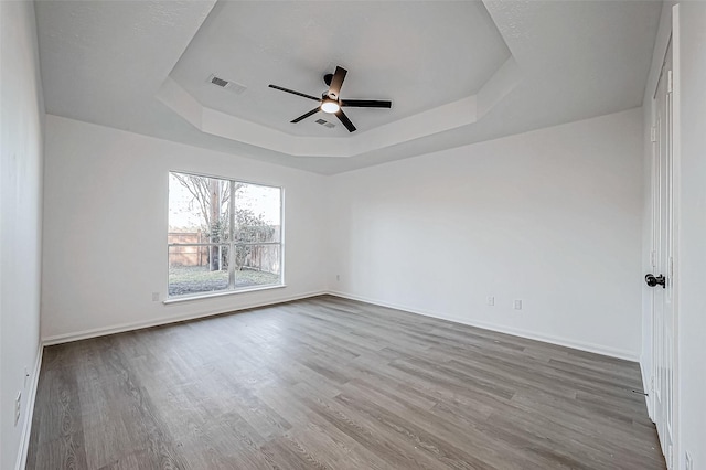 spare room featuring wood-type flooring, a tray ceiling, and ceiling fan