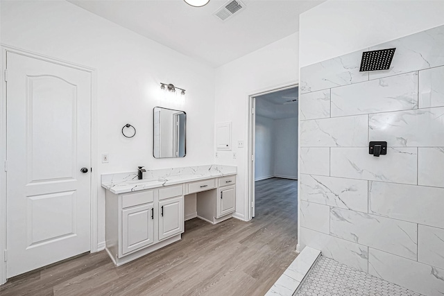 bathroom with vanity, wood-type flooring, and tiled shower