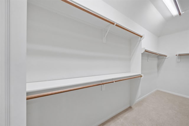 walk in closet with light carpet and lofted ceiling