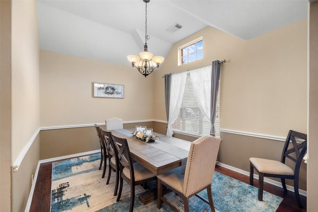 dining space with hardwood / wood-style floors, vaulted ceiling, and an inviting chandelier