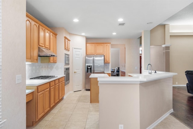 kitchen with tasteful backsplash, stainless steel appliances, a kitchen island with sink, sink, and light tile patterned floors