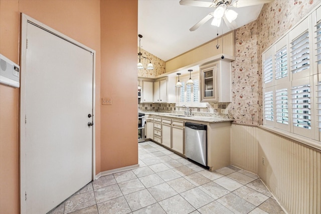 kitchen featuring pendant lighting, ceiling fan with notable chandelier, sink, appliances with stainless steel finishes, and cream cabinetry