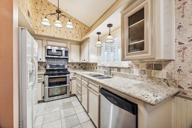 kitchen with sink, hanging light fixtures, light stone countertops, light tile patterned flooring, and stainless steel appliances