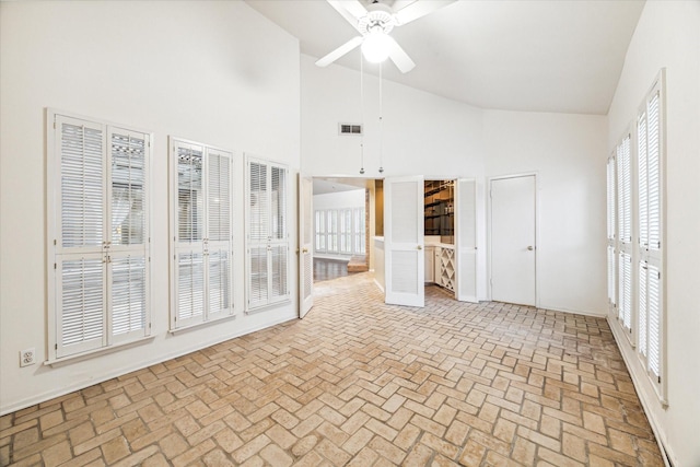 unfurnished living room with high vaulted ceiling and ceiling fan