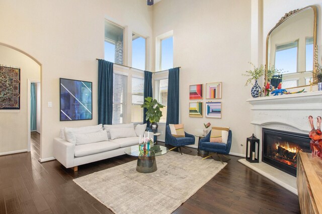 living room featuring a wealth of natural light, dark wood-type flooring, and a high ceiling