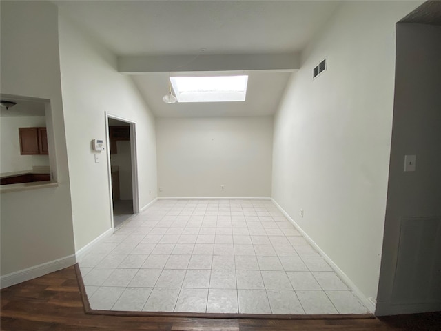 empty room with vaulted ceiling with beams and light hardwood / wood-style flooring