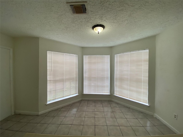 empty room with light tile patterned flooring and a textured ceiling