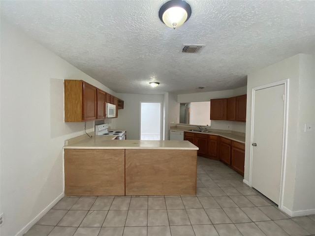 kitchen featuring kitchen peninsula, a textured ceiling, white appliances, sink, and light tile patterned flooring