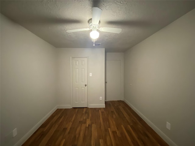 empty room featuring ceiling fan, dark hardwood / wood-style flooring, and a textured ceiling