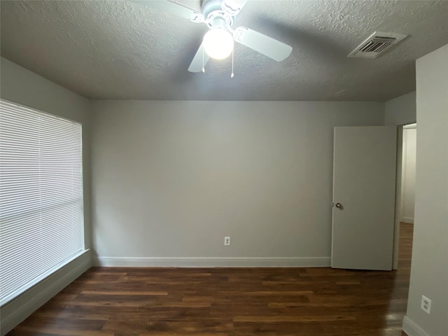 empty room featuring ceiling fan, dark wood-type flooring, and a textured ceiling