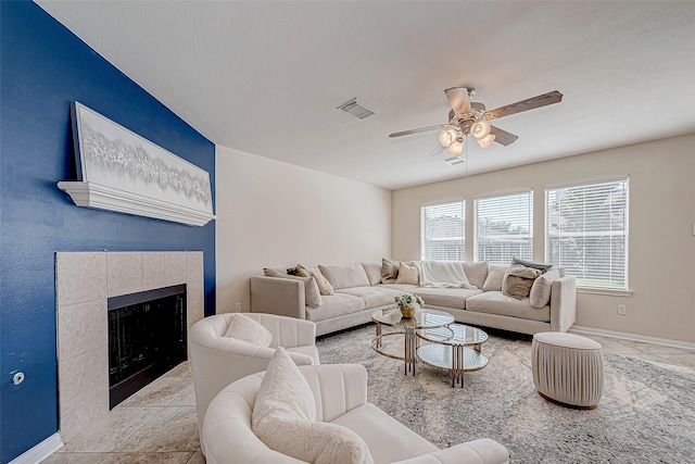 living room featuring a tile fireplace, ceiling fan, and light tile patterned floors