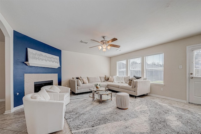 living room with a tile fireplace, a wealth of natural light, ceiling fan, and a textured ceiling