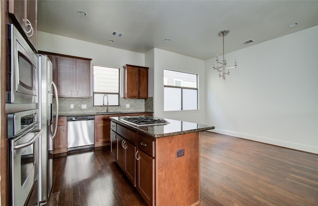 kitchen with appliances with stainless steel finishes, tasteful backsplash, sink, dark hardwood / wood-style floors, and a kitchen island