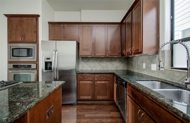 kitchen with sink, stainless steel appliances, tasteful backsplash, and dark stone countertops