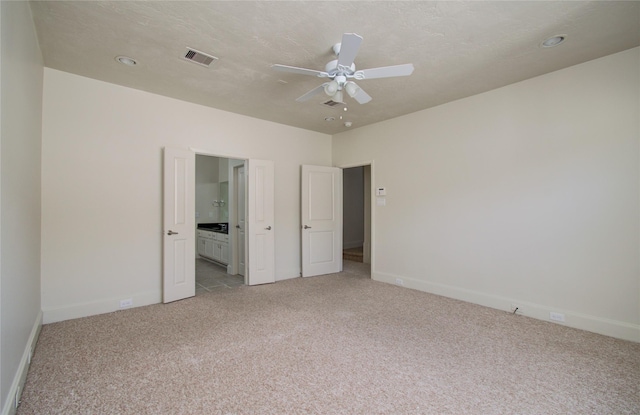 unfurnished bedroom with ensuite bath, ceiling fan, and light carpet