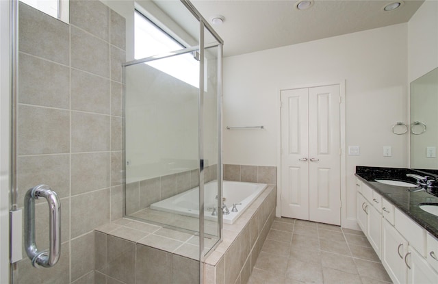 bathroom with tile patterned floors, tiled bath, and vanity