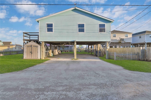 view of front facade with a front lawn, a storage unit, and a carport