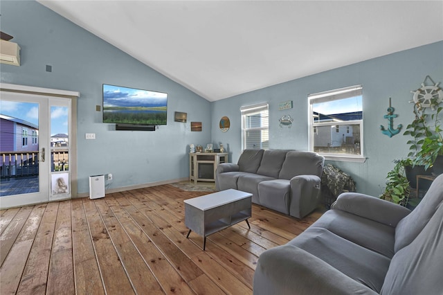 living room featuring a wall mounted air conditioner, light hardwood / wood-style floors, and high vaulted ceiling