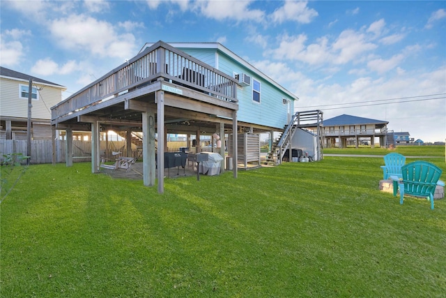 rear view of property featuring stairs, a lawn, a wooden deck, and fence