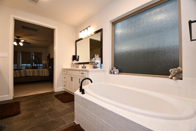 bathroom featuring tiled tub, ceiling fan, tile patterned flooring, and vanity