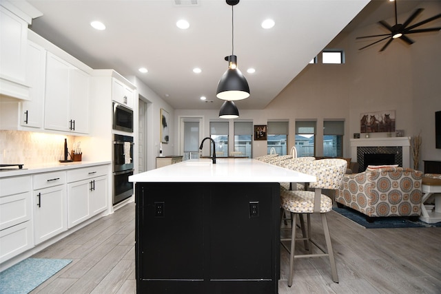 kitchen featuring light wood-type flooring, sink, decorative light fixtures, a center island with sink, and a breakfast bar area