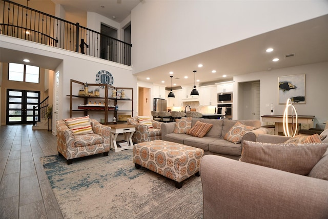 living room featuring dark hardwood / wood-style flooring, a towering ceiling, sink, and french doors