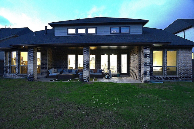 back of property with a lawn, a patio area, and an outdoor hangout area