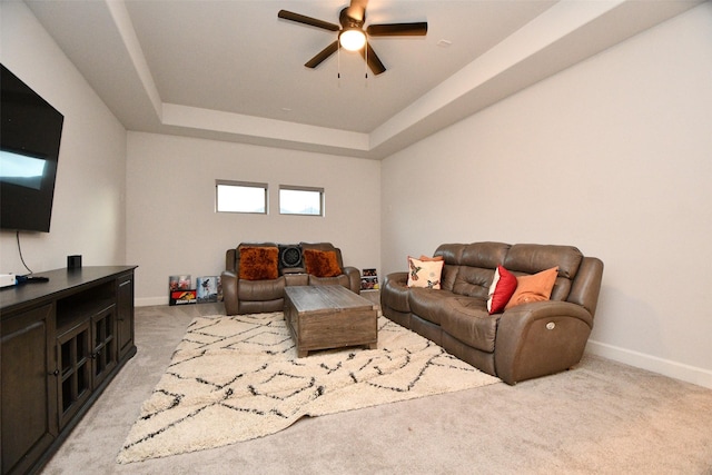 carpeted living room with a tray ceiling and ceiling fan